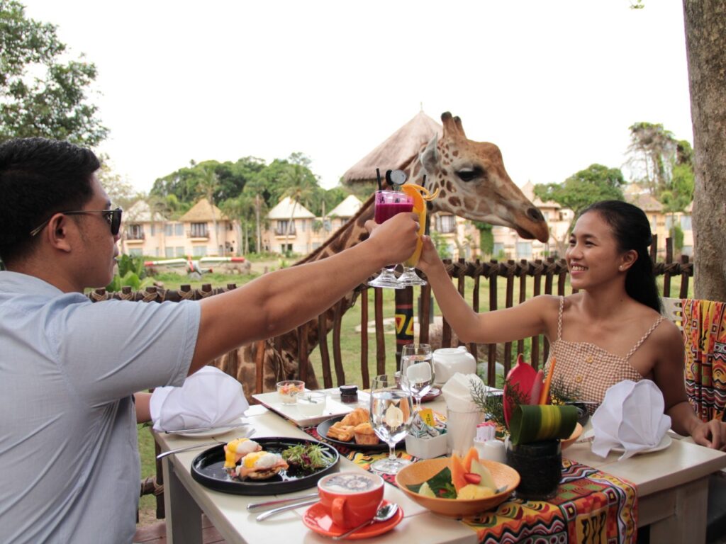 A couple enjoying breakfast with the giraffe at Bali Safari and Marine Park
